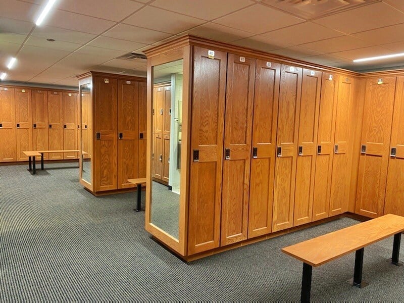 Locker room with mirrors, wooden lockers, and benches