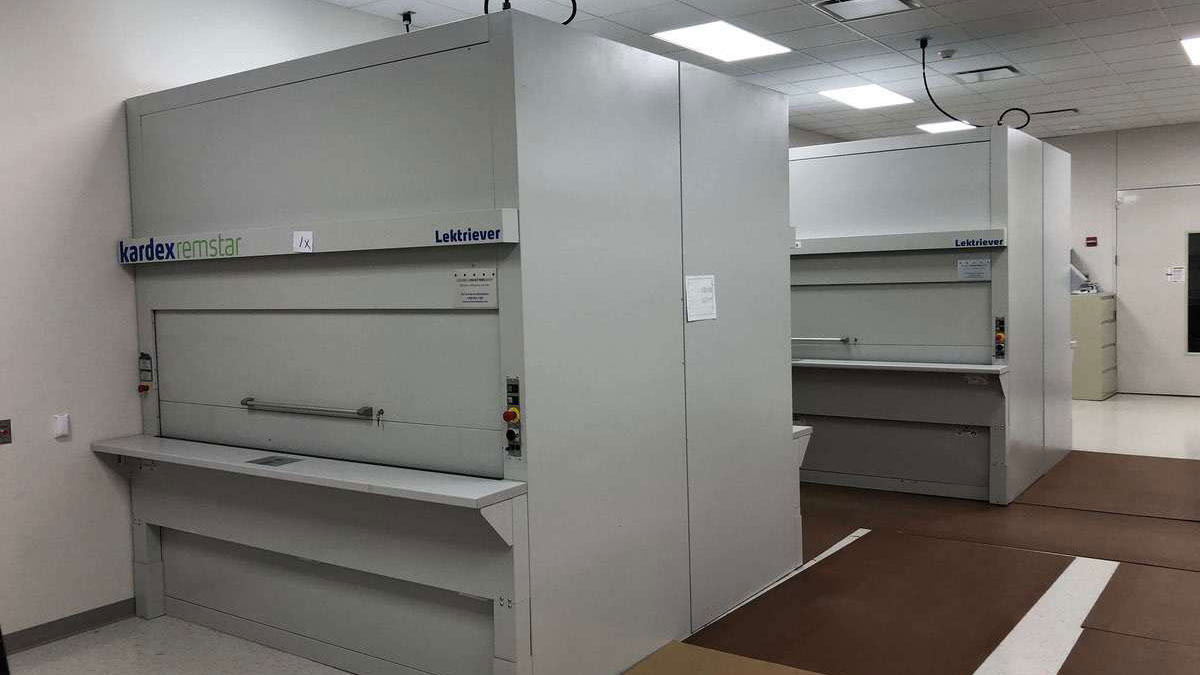 Dual Kardex Lektriever vertical carousel filing systems in a clean records room, both with the access ports closed, ready for operation