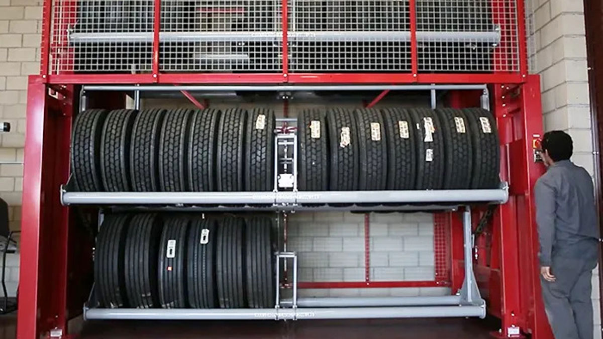 Heavy-duty vertical tire storage carousel in a red frame, used in auto service or warehouse environments
