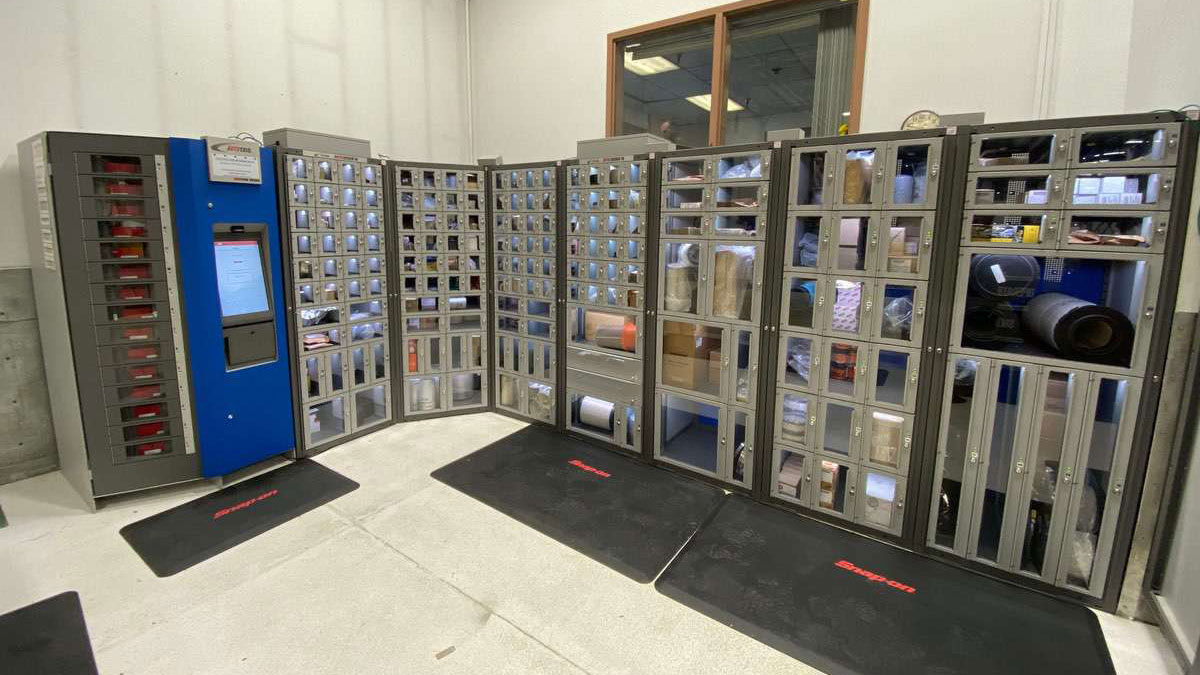 Curved configuration of vending machines with transparent locker windows storing industrial supplies in a tool crib area
