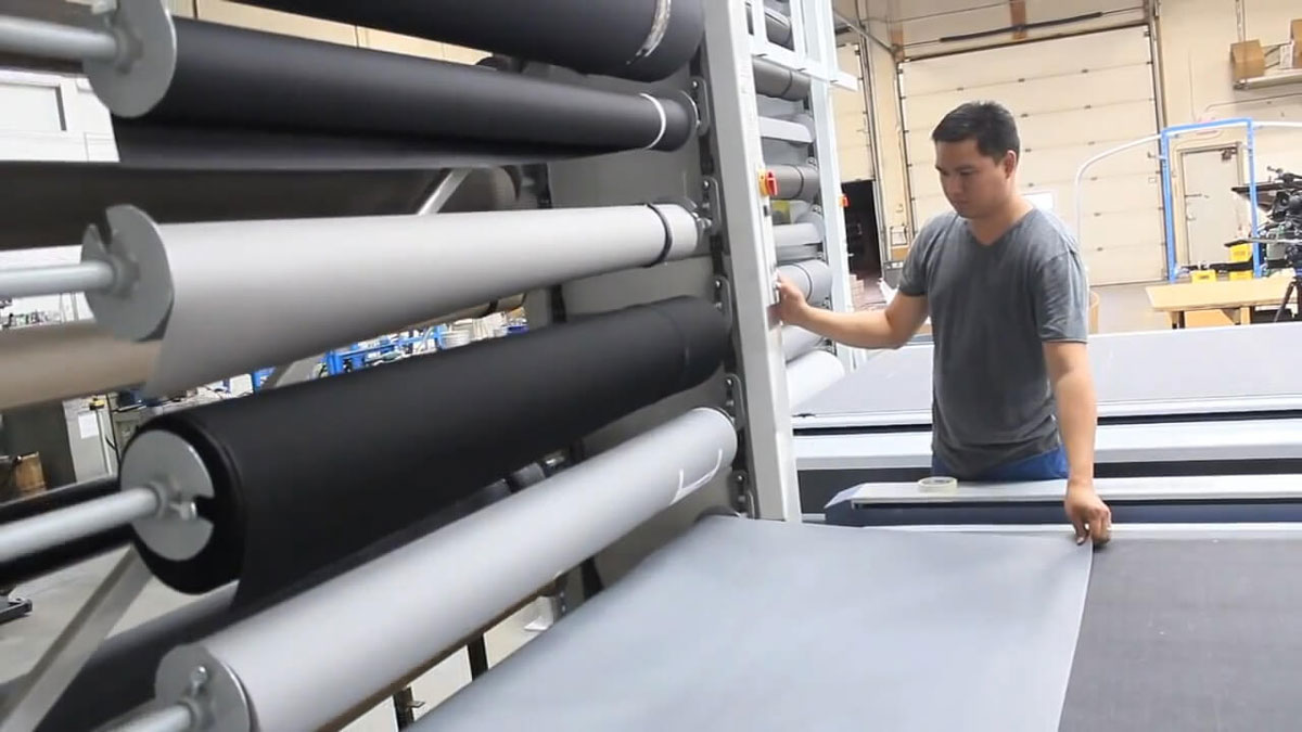 Worker operating a textile carousel with integrated cutting table for easy roll selection and fabric cutting