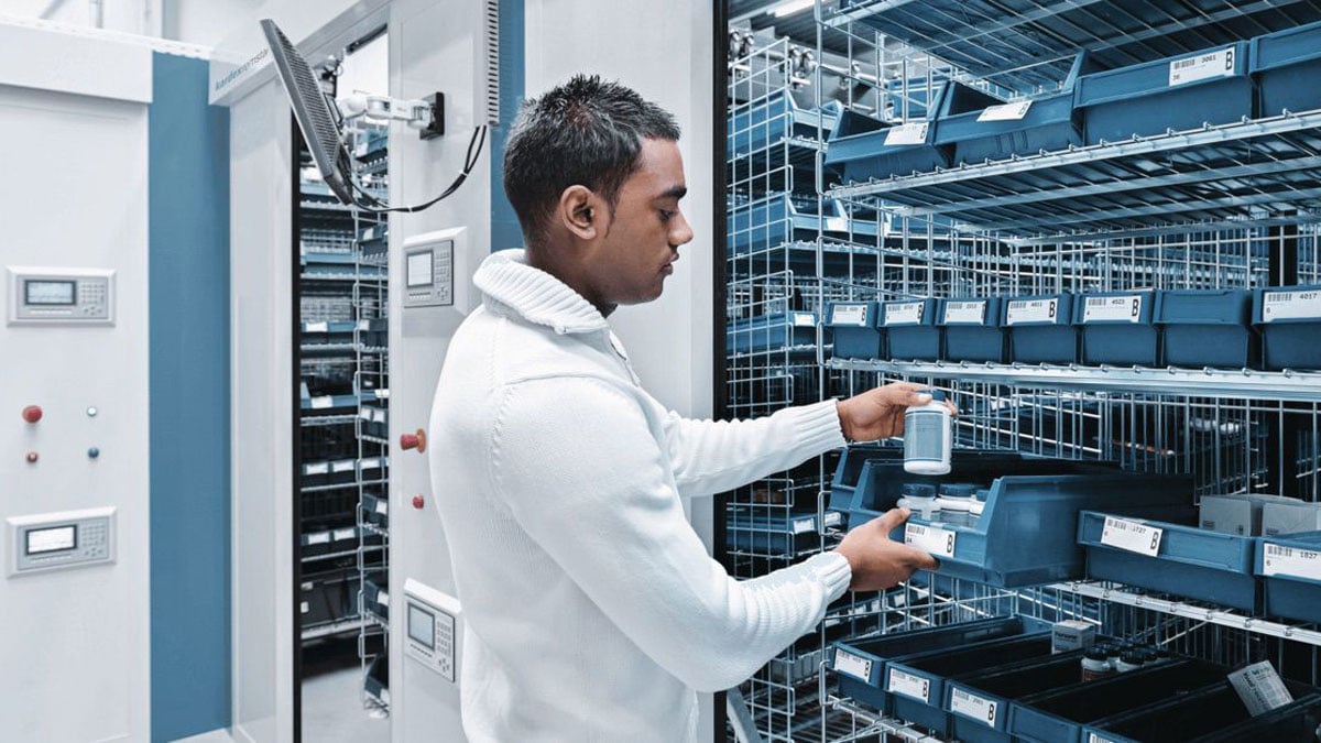 Warehouse employee retrieving small items from a horizontal carousel to speed order picking