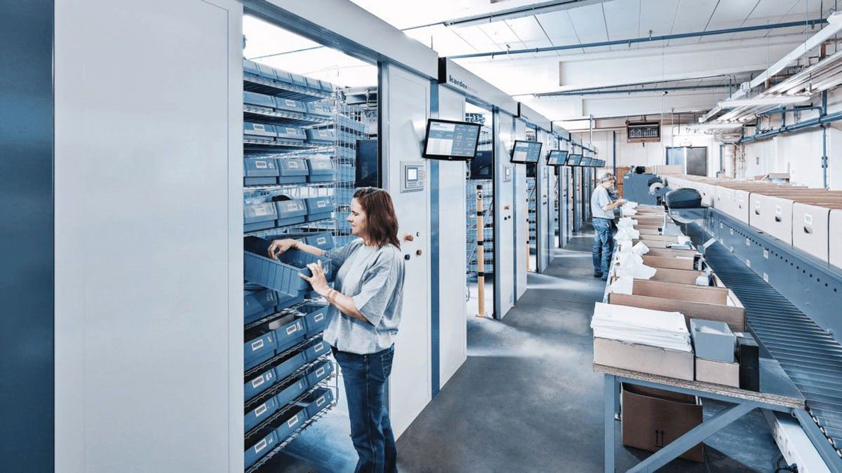 Female operator accessing goods from a horizontal carousel storage system in a modern warehouse using a goods-to-person picking strategy with integrated display panels