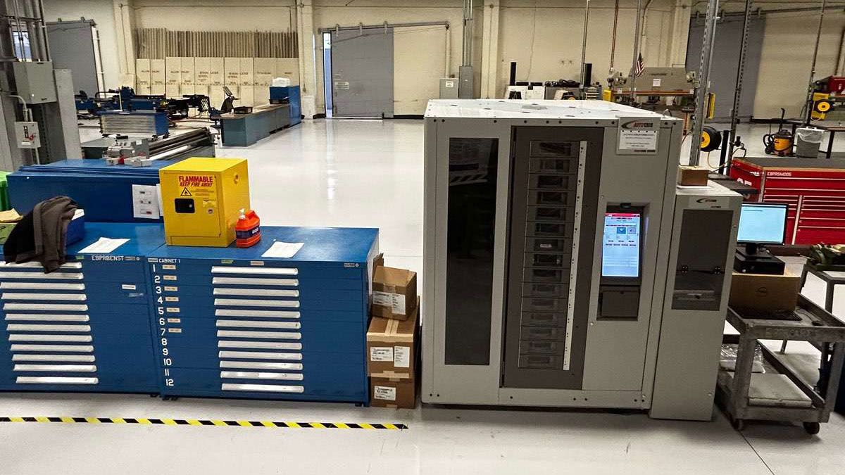 Standalone industrial vending machine with touchscreen in a clean, modern manufacturing facility, enabling automated inventory control