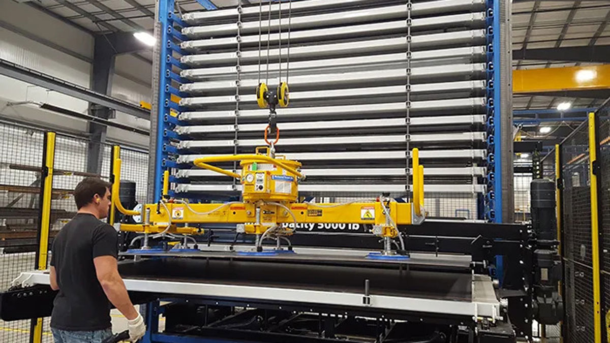 Worker operating a vertical lift module for storing and retrieving sheet metal with an automated vacuum lifter