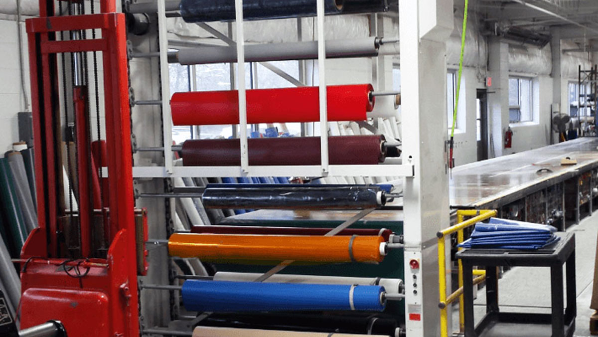 Fabric roll storage carousel system with color-coded rolls, optimized for vertical warehouse space utilization