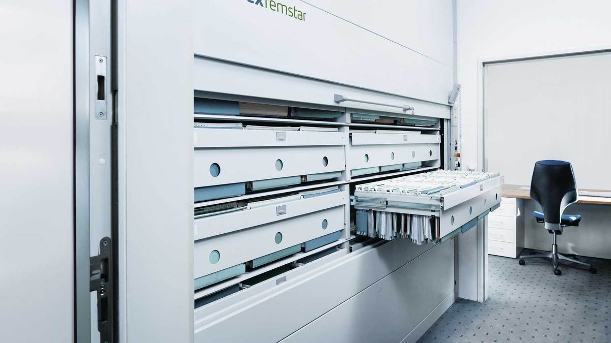 High-resolution view of a Kardex Remstar automated filing cabinet with extended drawer holding categorized documents in hanging folders.