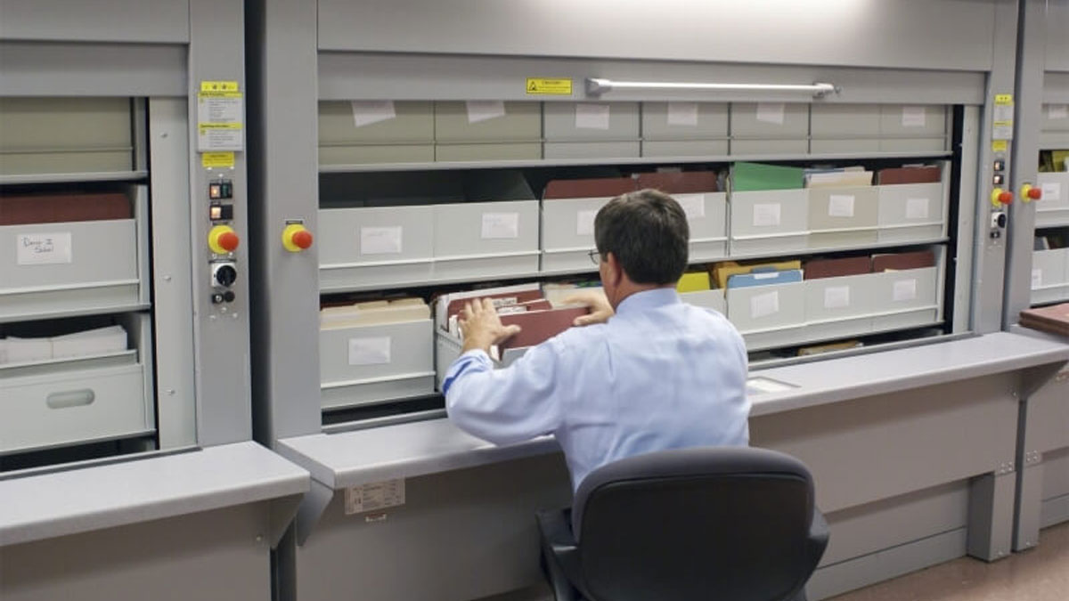 Office worker accessing and organizing files in an automated vertical carousel system designed for secure and ergonomic document storage