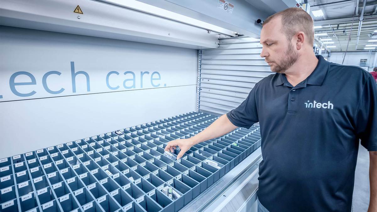 Worker accessing small inventory parts from an organized bin system inside a Kardex Remstar VLM, emphasizing ergonomic picking and item visibility