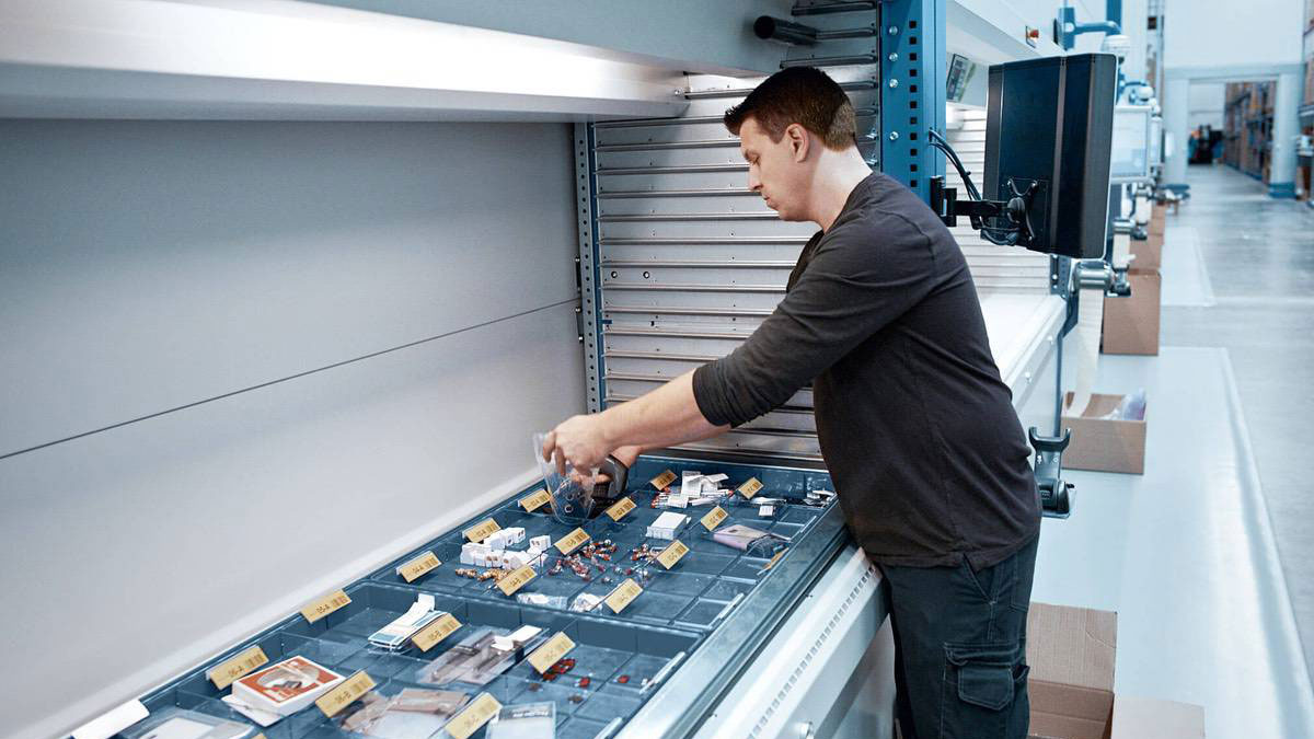 Operator selecting components from organized bins inside a VLM