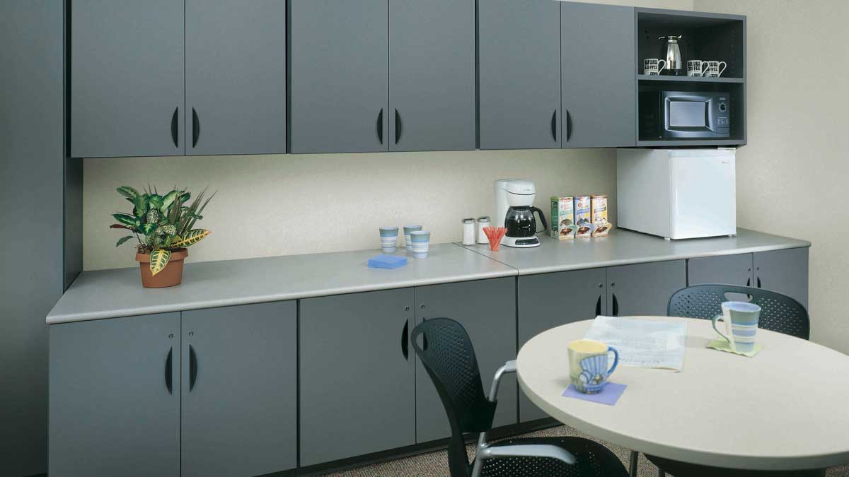 Grey cabinetry with built-in microwave mini fridge and floating shelves in break room