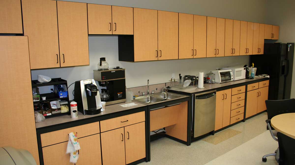 wood cabinets with coffee station sink microwave and dishwasher along break room wall.