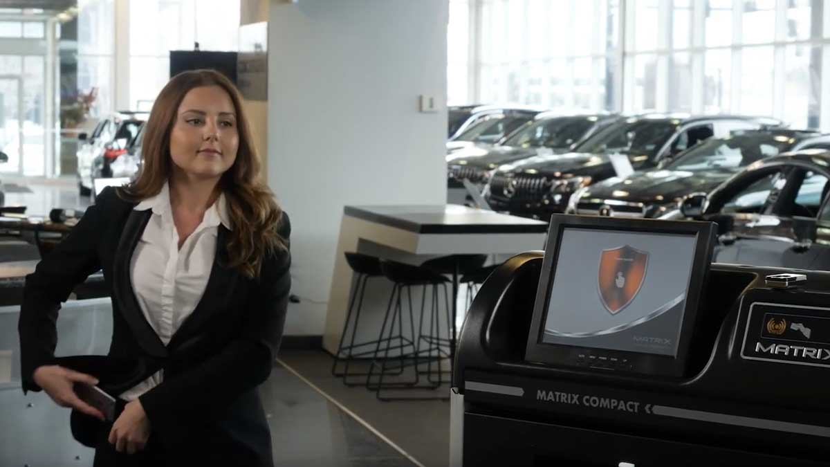 Employee accessing touchscreen on compact electronic key cabinet for secure key retrieval in showroom