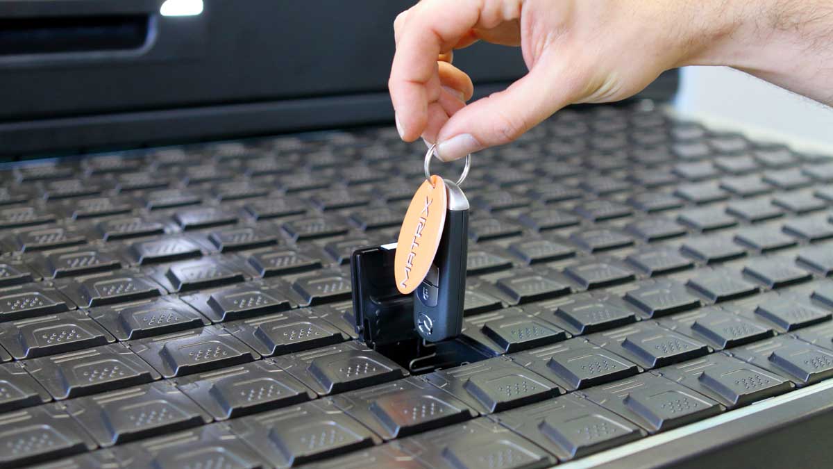 operator loading key fob into designated slot on electronic key cabinet tray for inventory management
