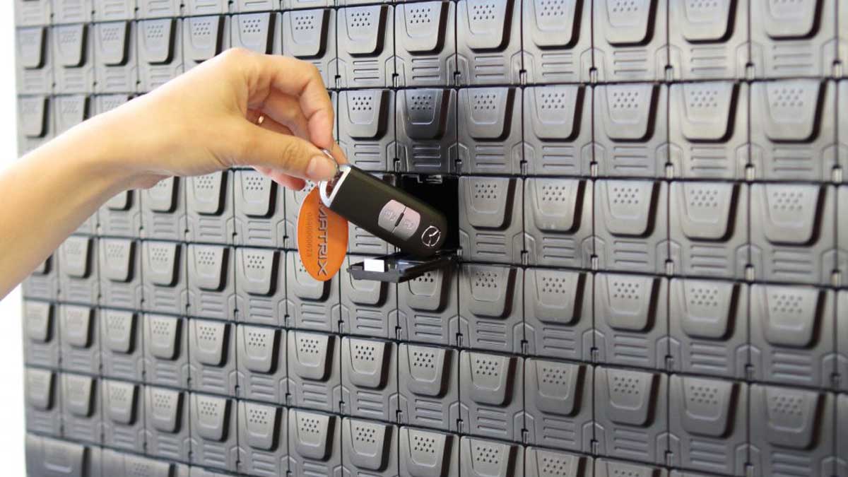 User inserting key fob into wall mounted electronic key panel slot for secure check in and monitoring