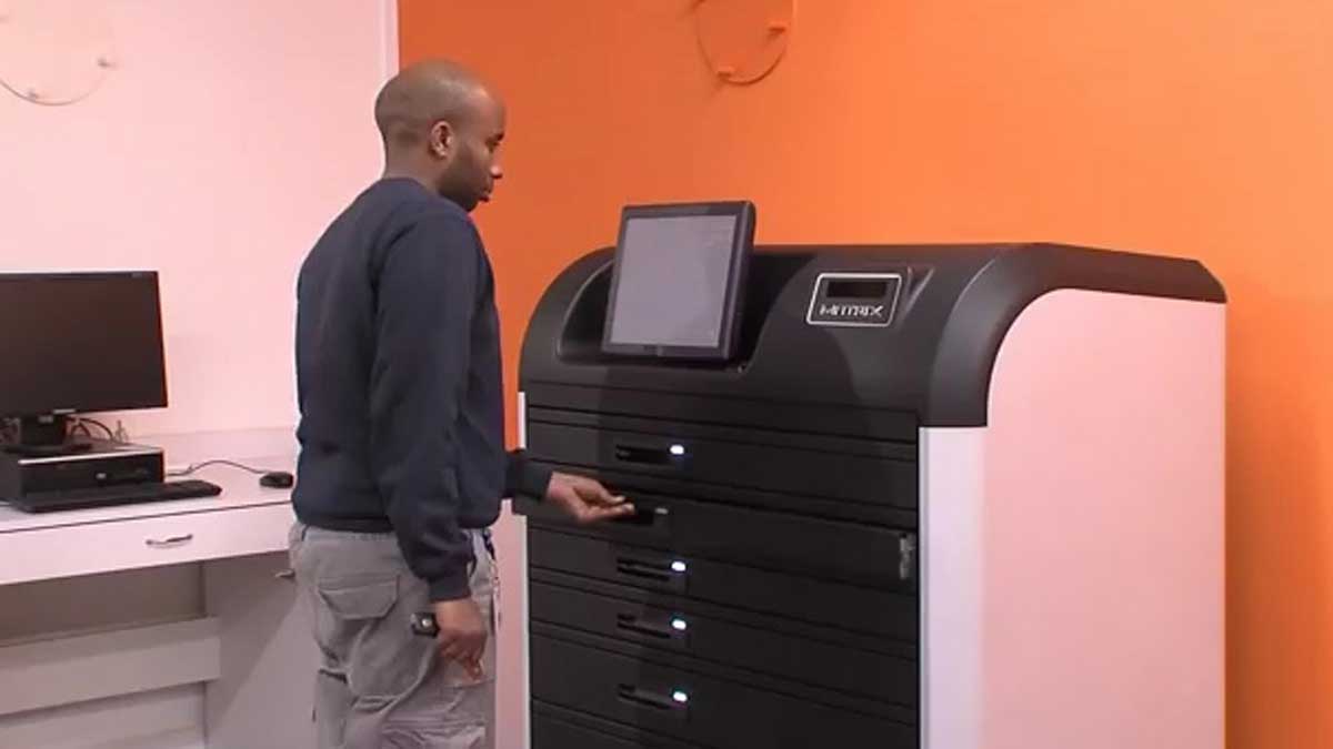 Technician accessing drawer on electronic key cabinet in workshop for controlled key issuance