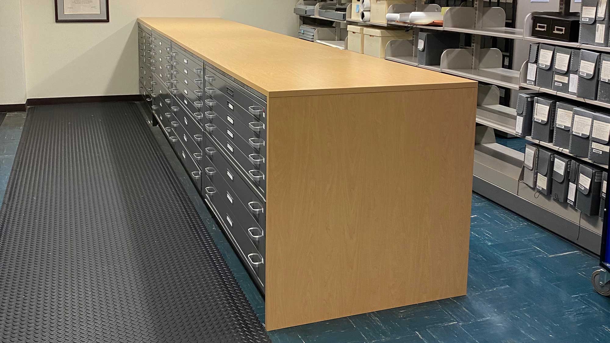 Central island of flat-file cabinets featuring laminate work surface in archival storage room.
