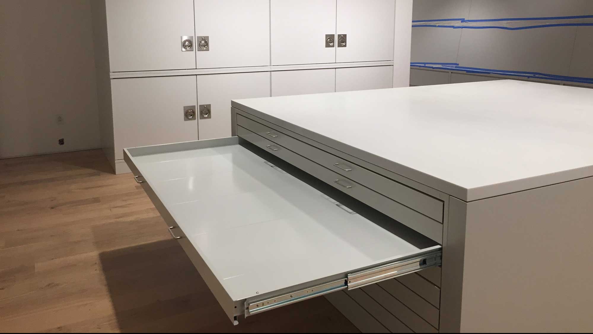 Flat-file worktable with large pull-out drawer and glass display top in conservation studio.