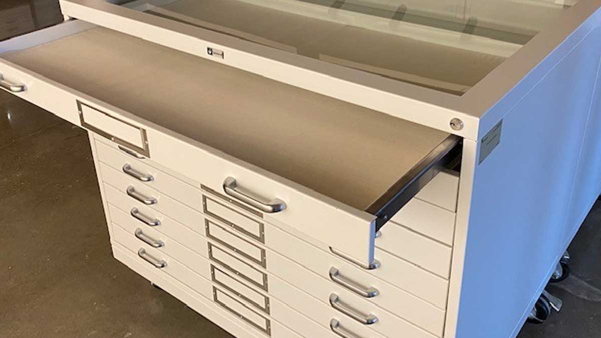 Studio flat-file cabinets with pull-out trays and glass display tops for archival prints and artwork.