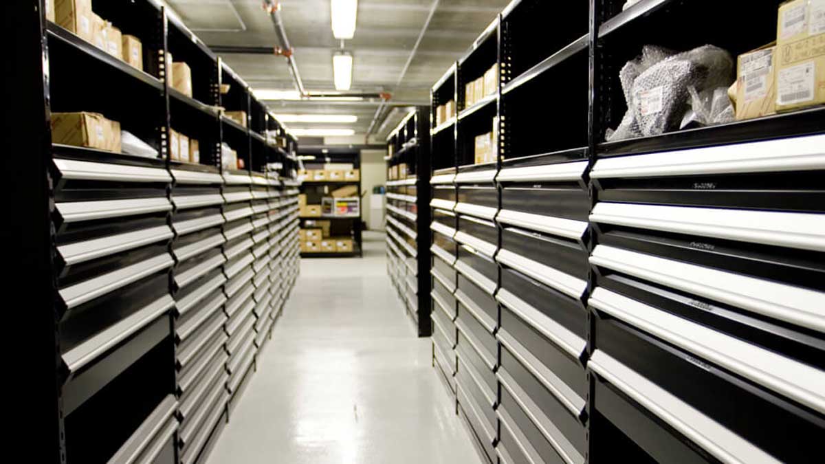 Long corridors of black modular drawer cabinets with white drawer handles in a parts depot.