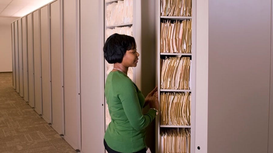 Woman accessing rotating file cabinets designed for compact vertical file storage