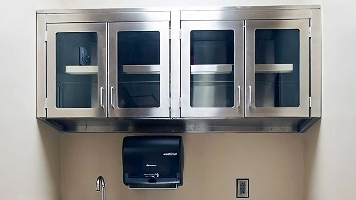 stainless steel wall cabinets mounted above sink offering enclosed storage for medical supplies at workstation