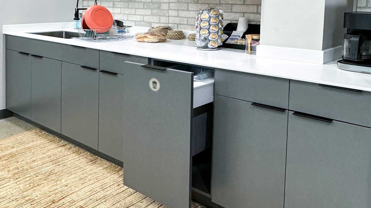 grey breakroom cabinetry with white countertop, coffee station, and integrated trash drawer
