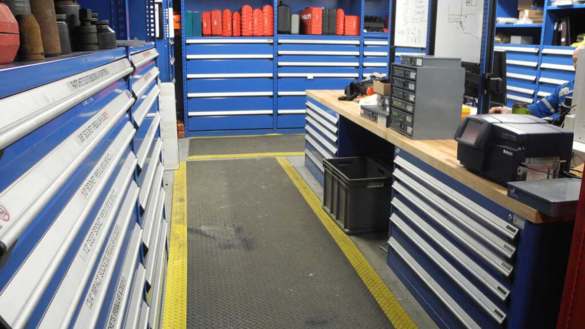Heavy-duty blue and yellow modular drawers and shelving holding mining components in a warehouse