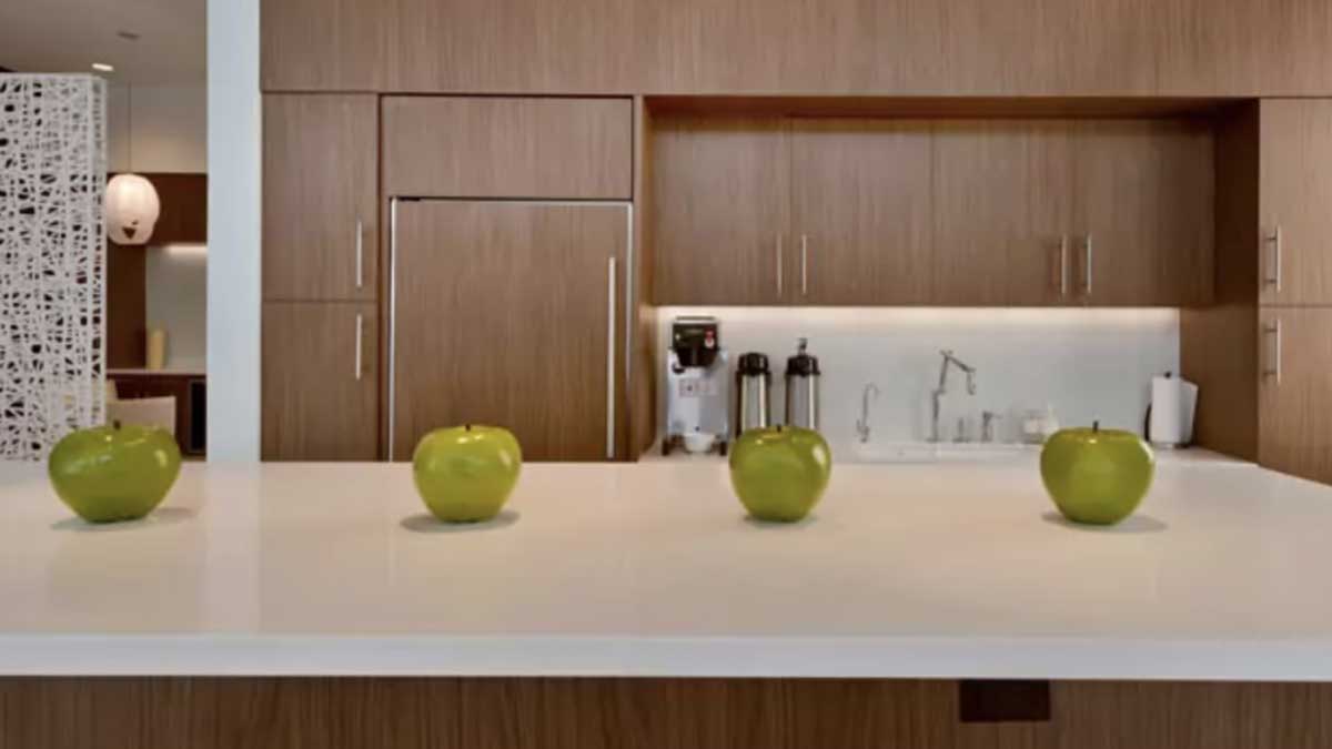 white countertop with green apples and coffee brewer against wood panel cabinets