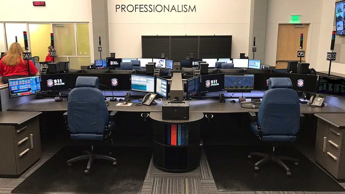 Rows of 911 dispatch workstations with wall-mounted displays