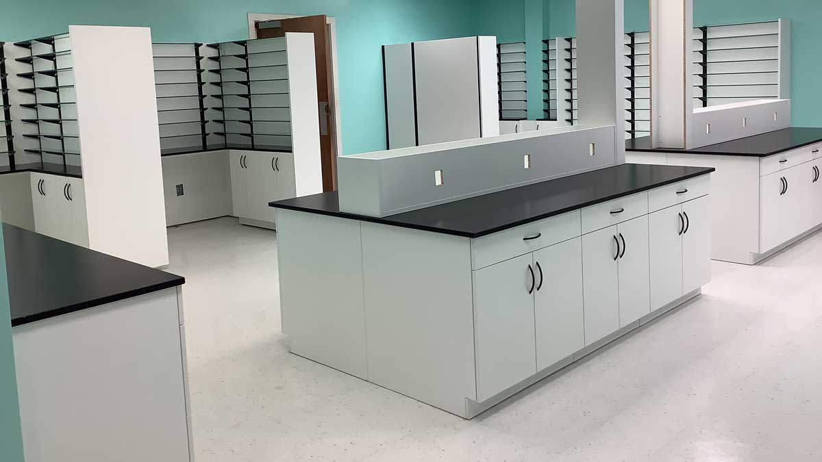 White laboratory storage cabinets with black countertops, perfect for efficient lab organization and workspace.
