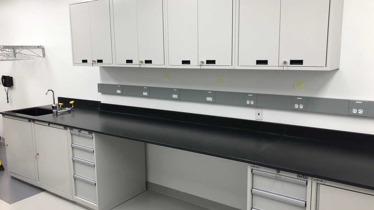 laboratory metal casework with integrated sink, drawers, upper cabinets, and electrical outlets for efficient workspace
