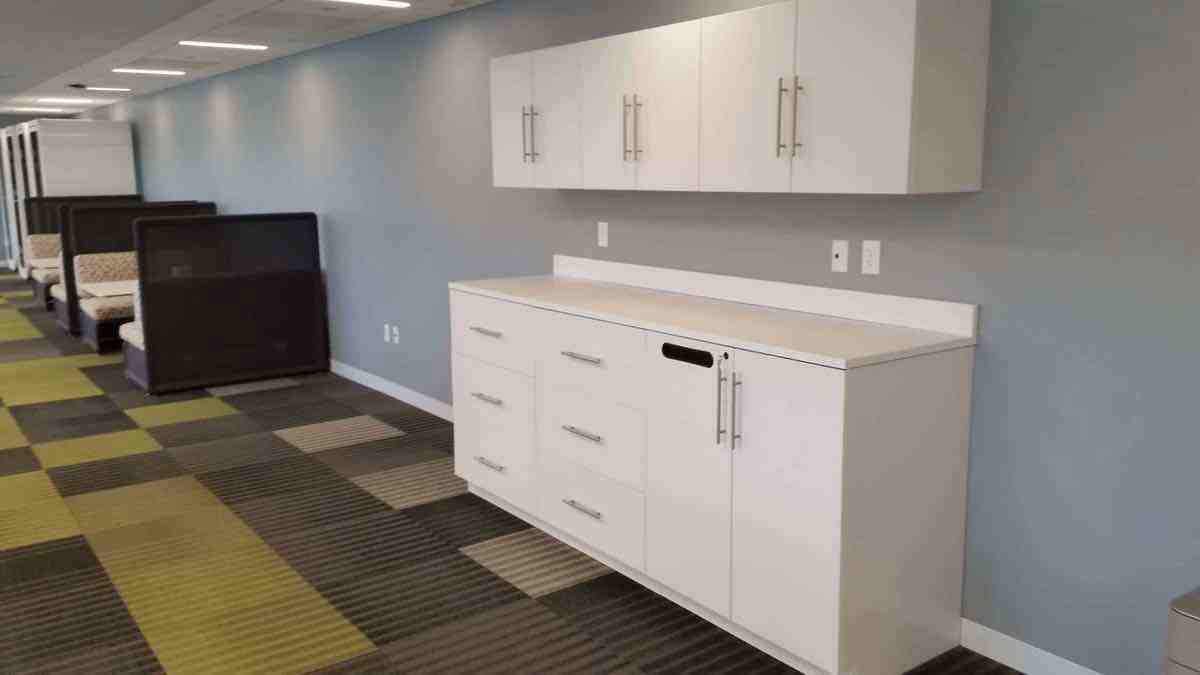 modern white modular casework with wall-mounted upper cabinets in office lounge area.