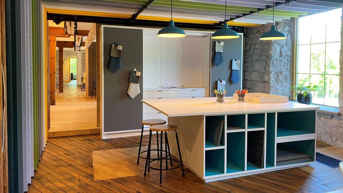 Modular island casework in creative design studio with open shelving and pendant lighting