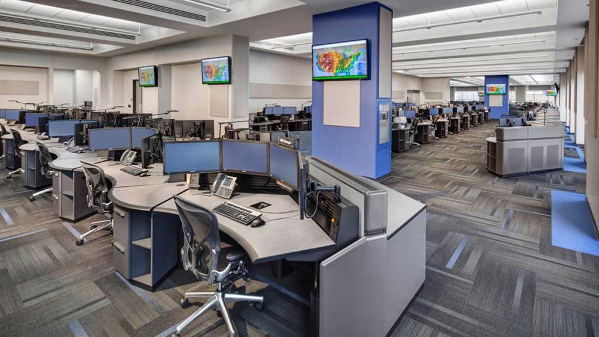 Public safety command center control room with multiple monitoring screens and workstation seating