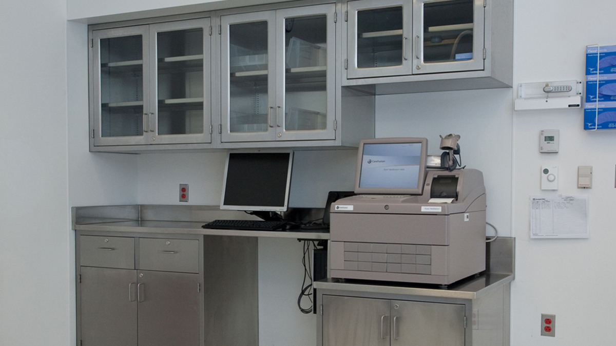 stainless steel workstation with upper glass door cabinets and medical equipment storage area