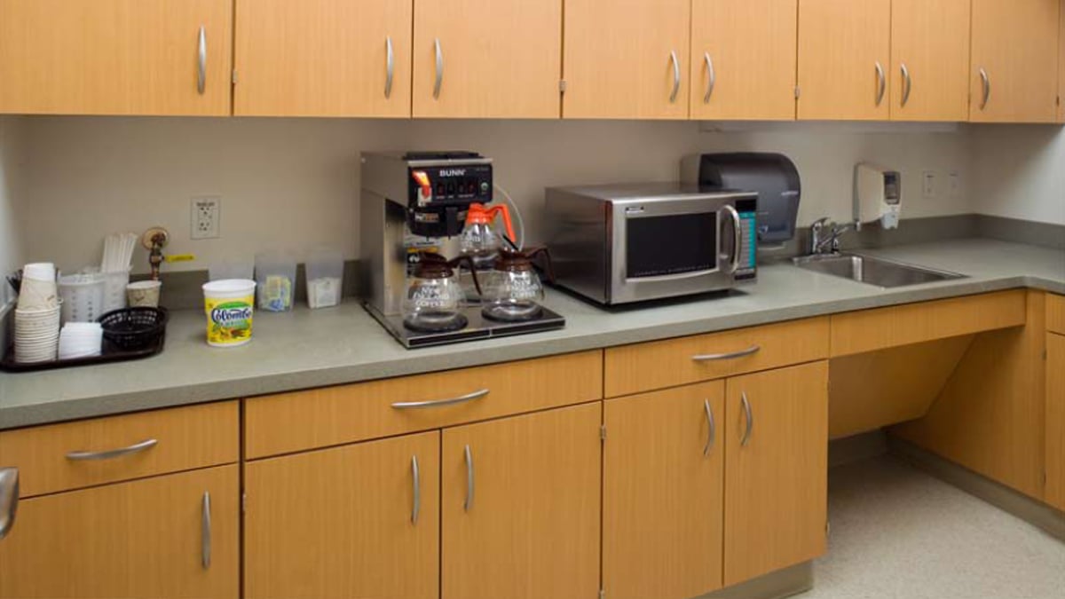 Corporate breakroom furniture with compact countertop, microwave, sink, and coffee station for employees