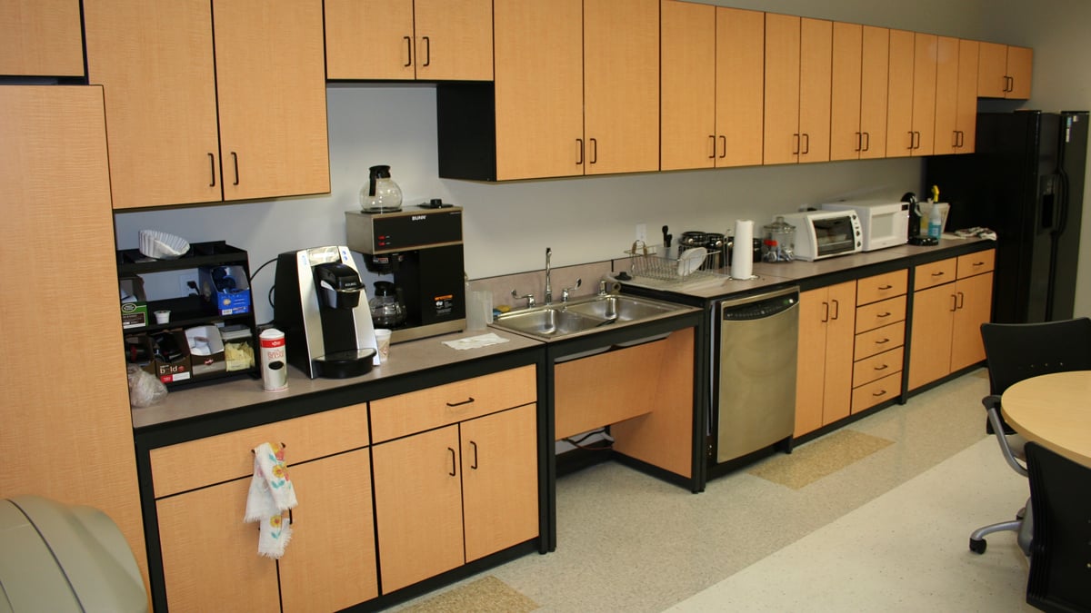 School or university breakroom furniture wall of wood finish cabinets with integrated appliances