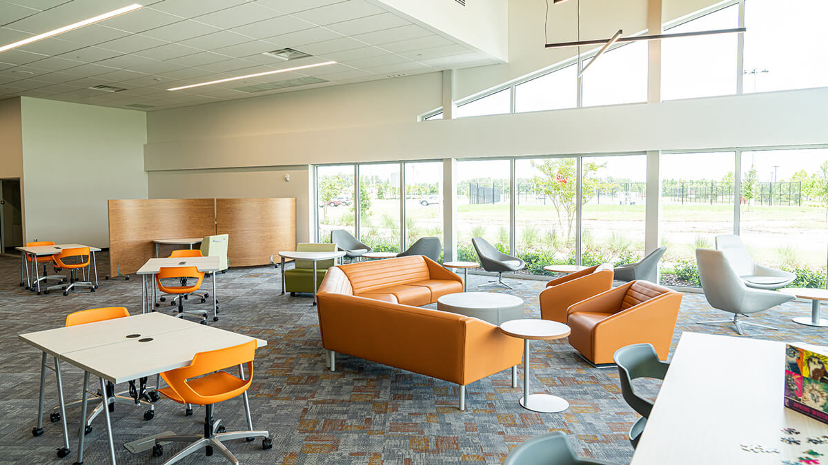 Library collaborative workspace with chairs, worktables, and open shelving designed for group study and flexible learning