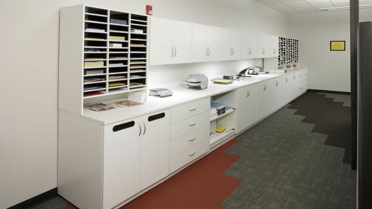 Modular casework system in mailroom copy room with adjustable cubbies and work surfaces for mail sorting