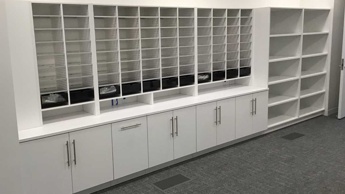 Mailroom storage setup with cubby shelves and rolling work tables for mail sorting and distribution