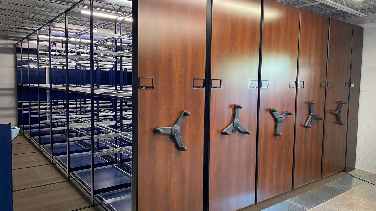 Mobile golf bag storage racks with wood veneer fronts in a country club bag room