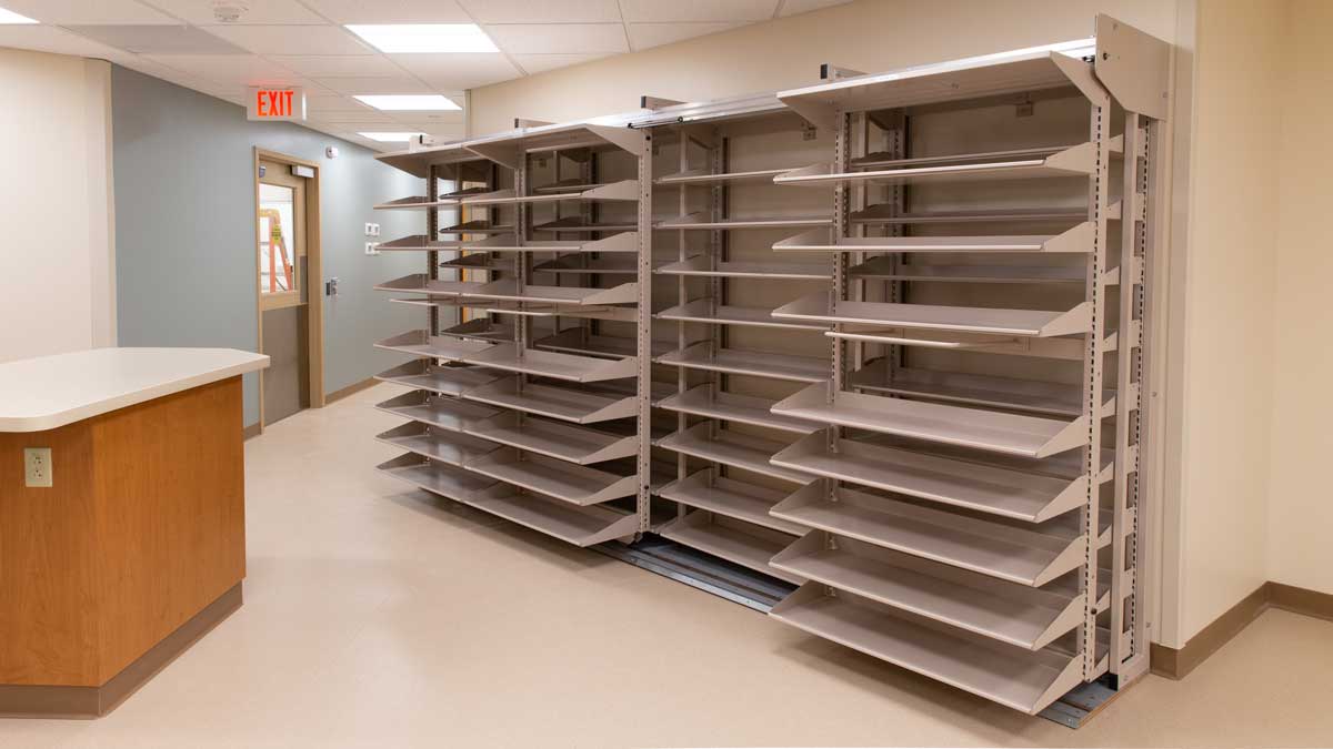Mobile shelving system in a pharmacy to increase storage capacity and improve inventory access