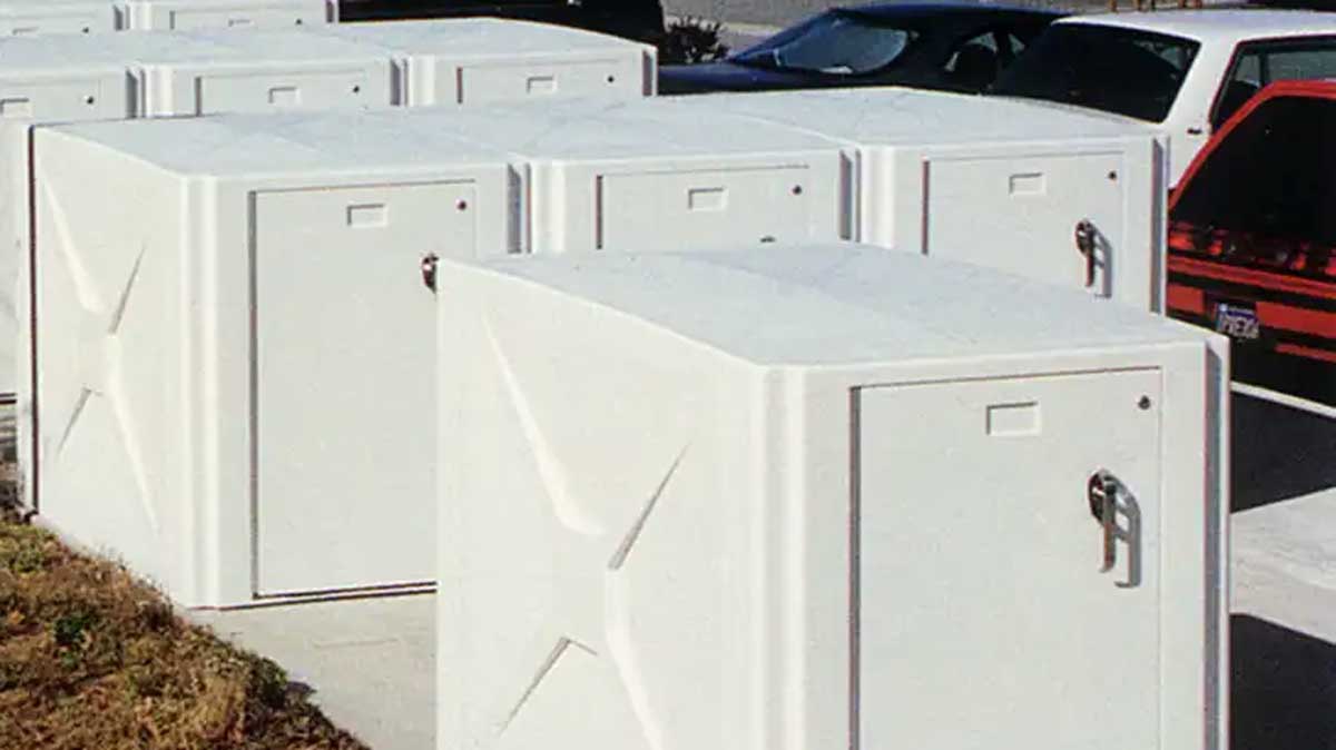Cluster of bike lockers arranged in a parking lot near parked vehicles for secure storage.