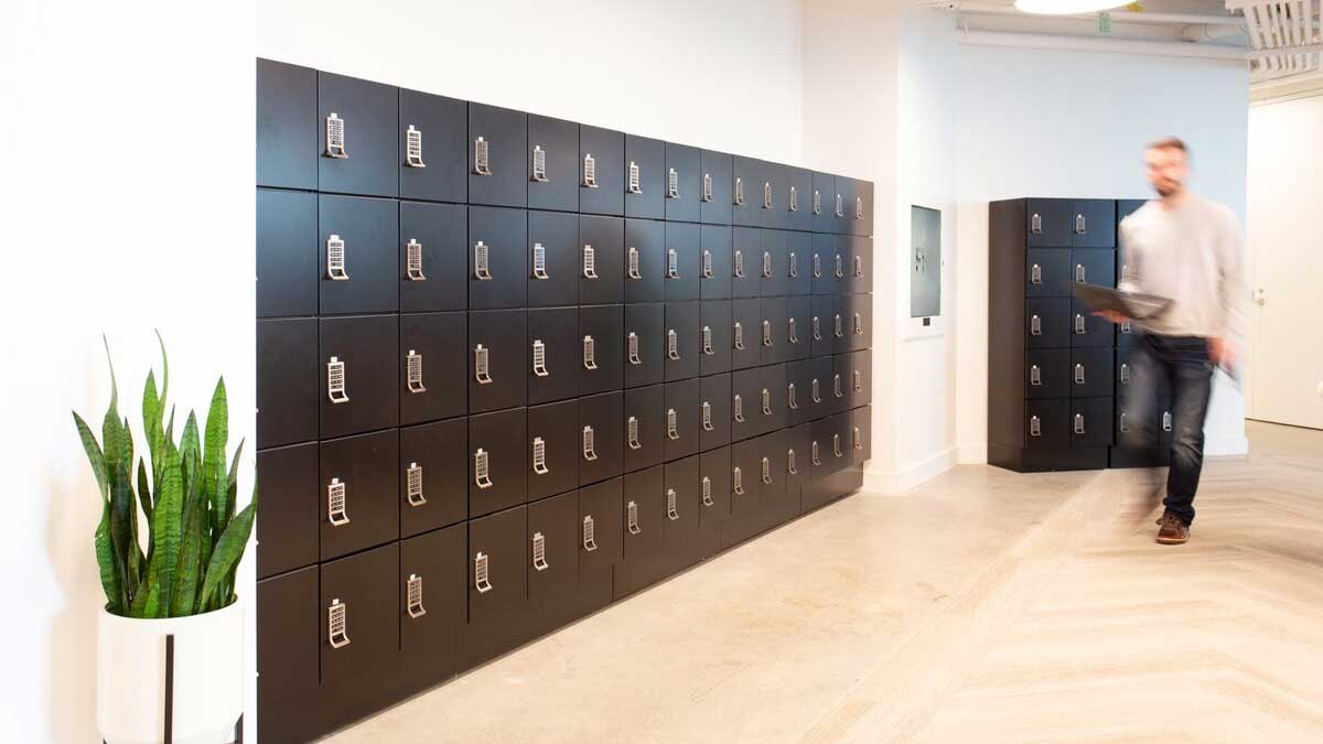 Black day-use lockers with keypad locks in corporate space with light wood herringbone floors