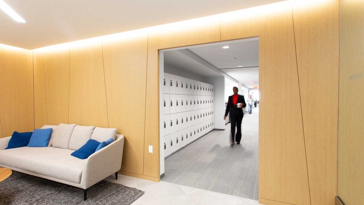 Employee locker room with white lockers and hallway leading into collaborative workspace 