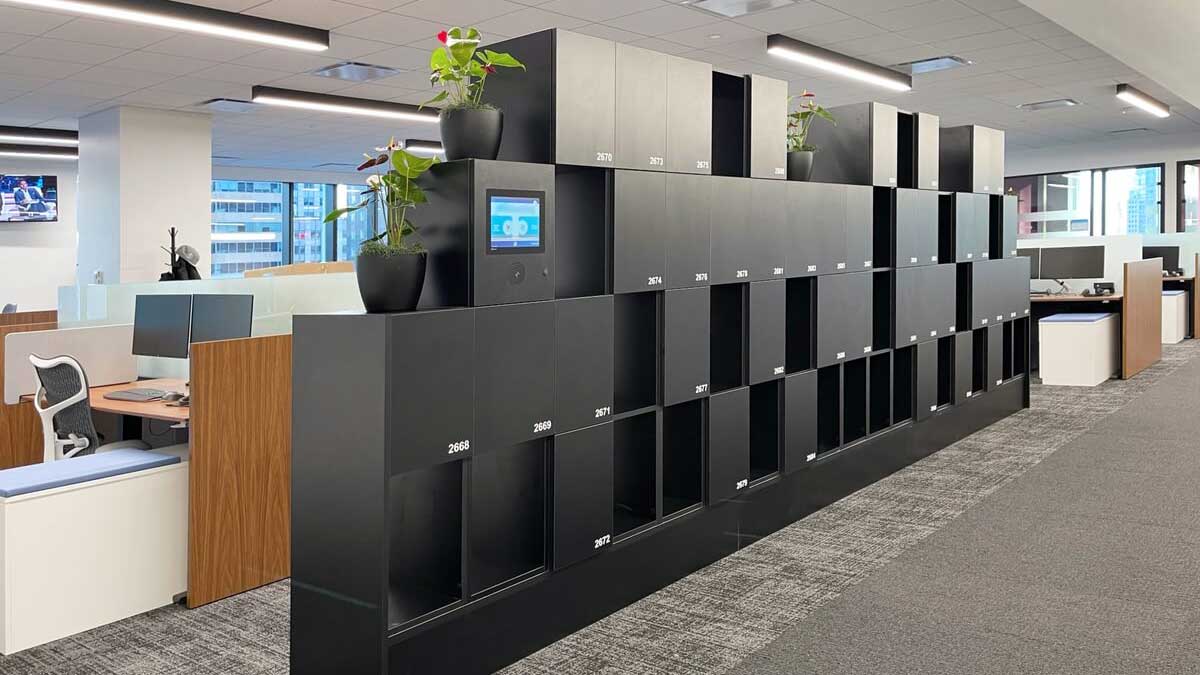 Smart black office locker system with integrated touchscreen and open workspace design