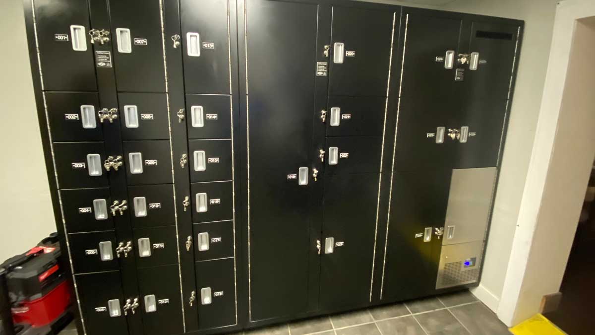 Public safety evidence lockers with black metal compartments and keyed small lockers in a secure storage room with gray tile flooring