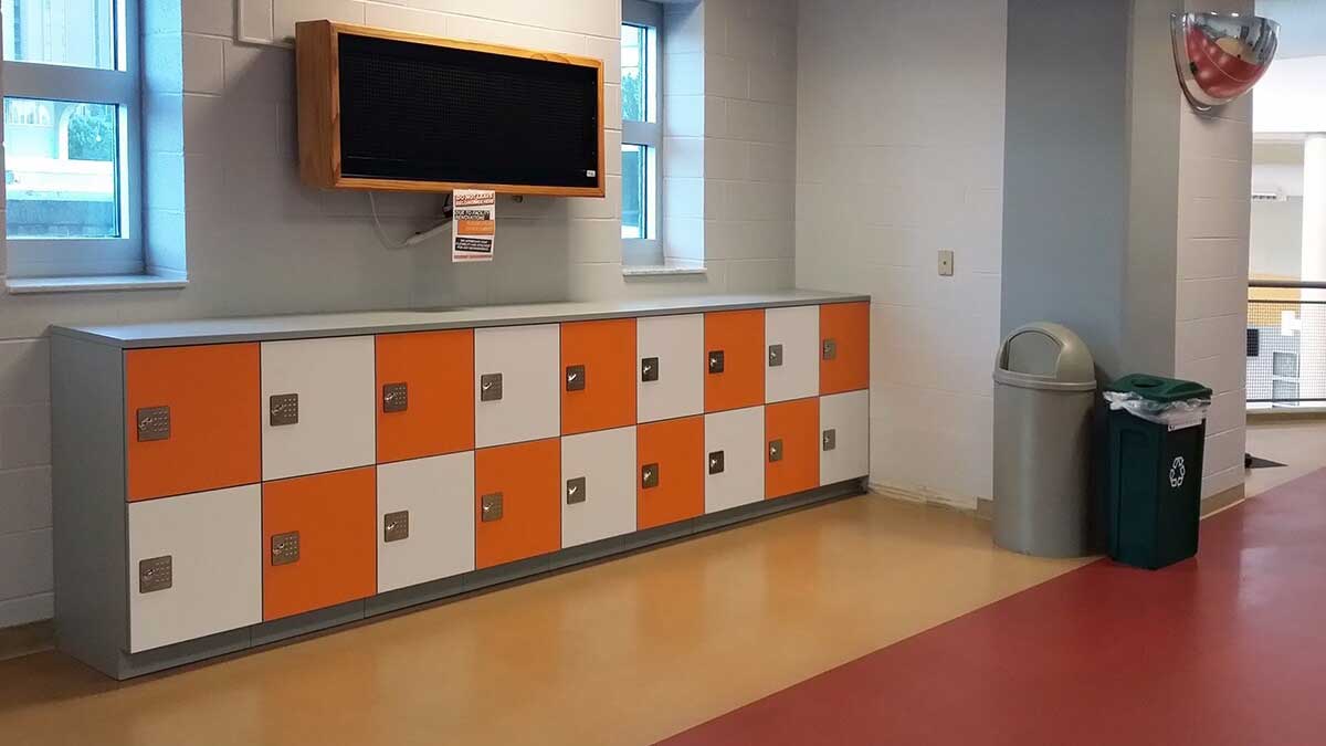 Compact orange and white storage lockers in a recreation or gym facility lobby