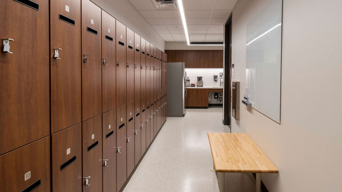 Functional PSAP locker room with whiteboard, wood bench, and personal storage compartments